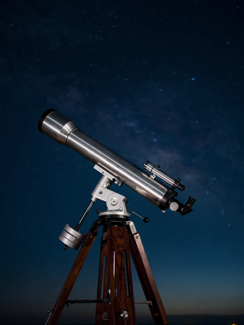 Professional telescope pointed towards a vibrant nebula in the night sky